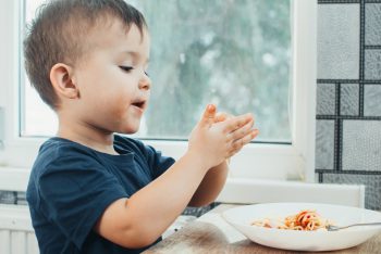 Ein kleiner Junge spielt mit seinem Essen