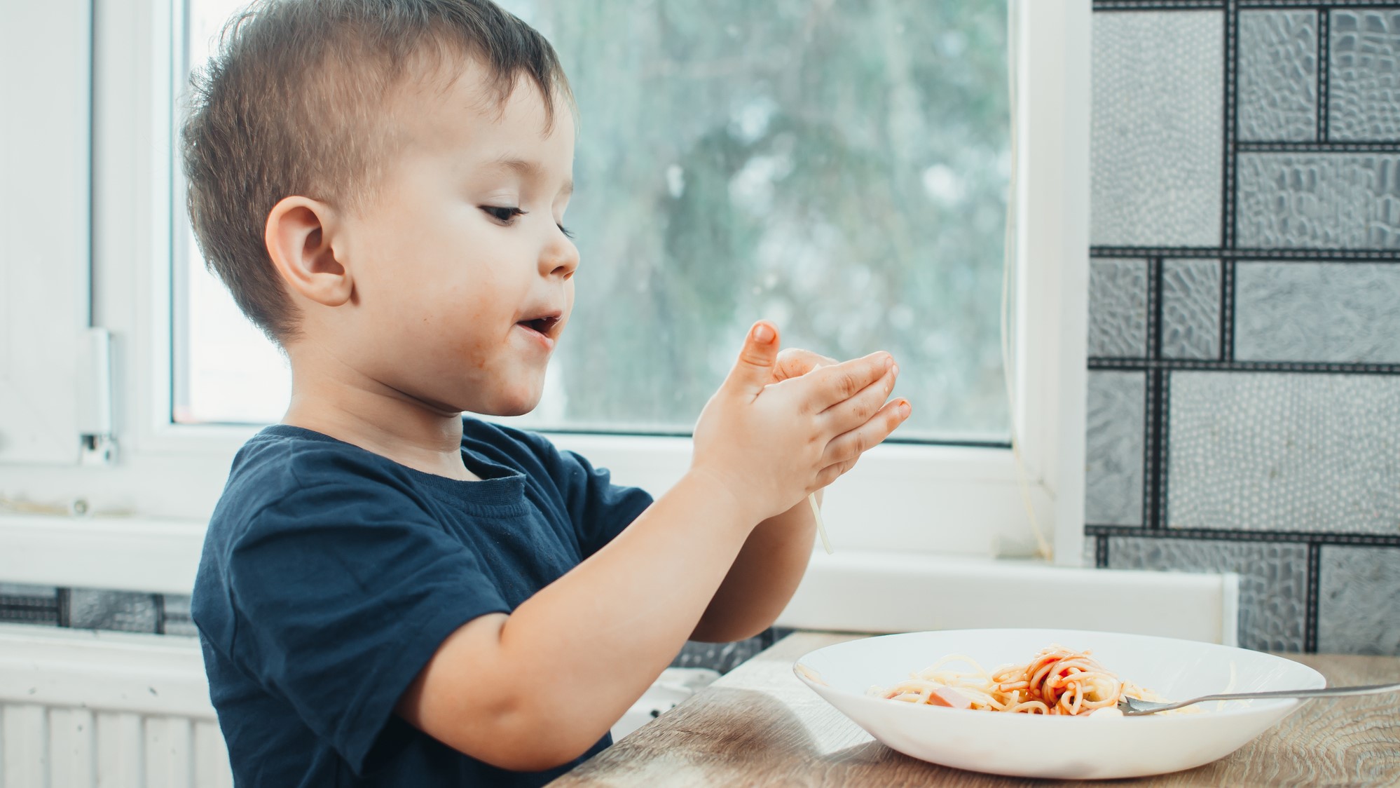 Ein kleiner Junge spielt mit seinem Essen