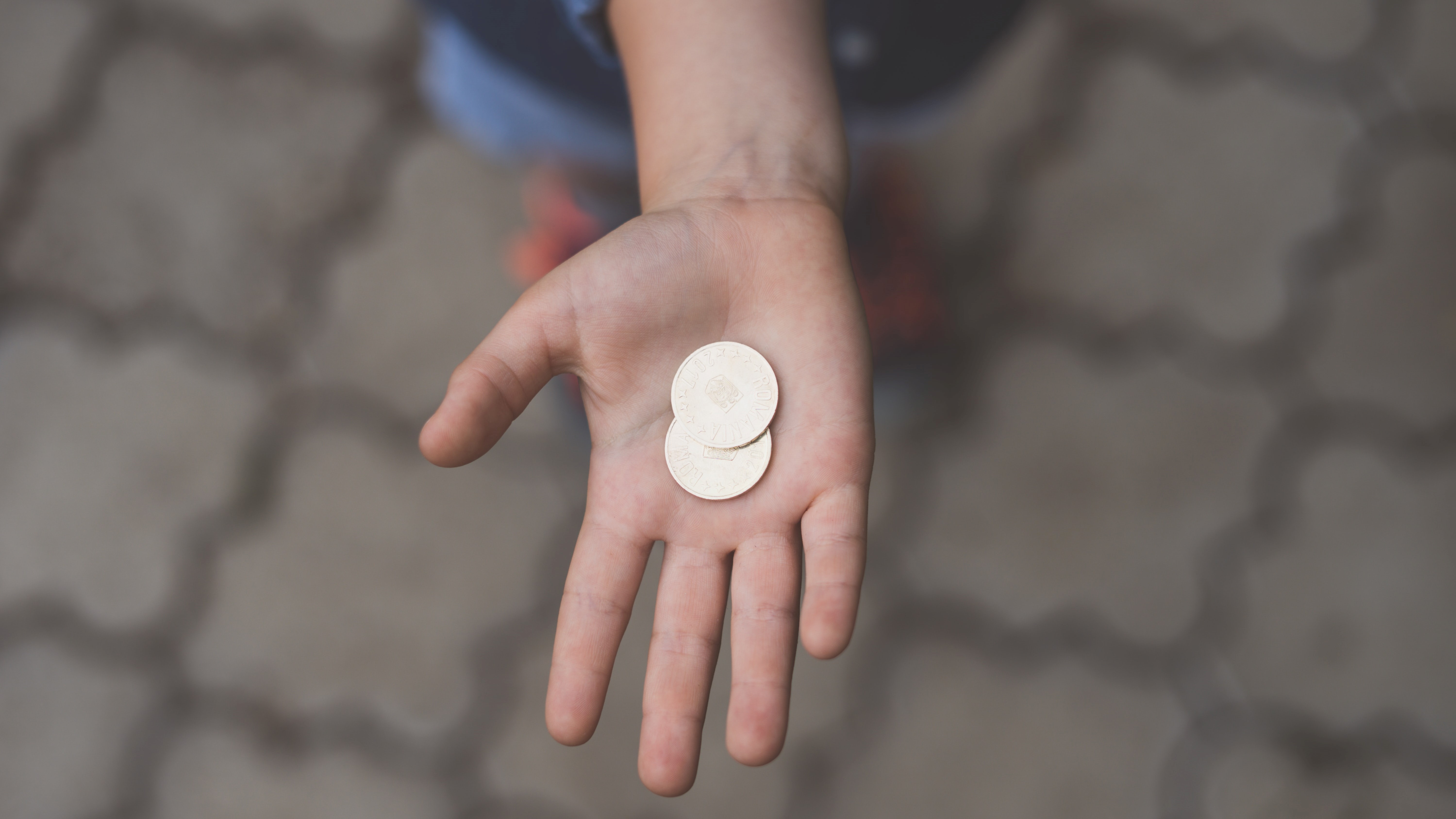 Eine Kinderhand mit zwei Münzen
