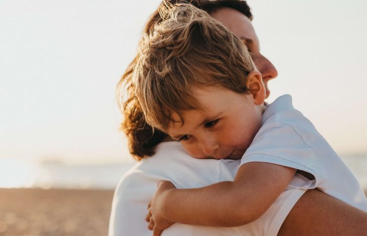 Ein kleiner Junge liegt in den Armen seiner Mutter