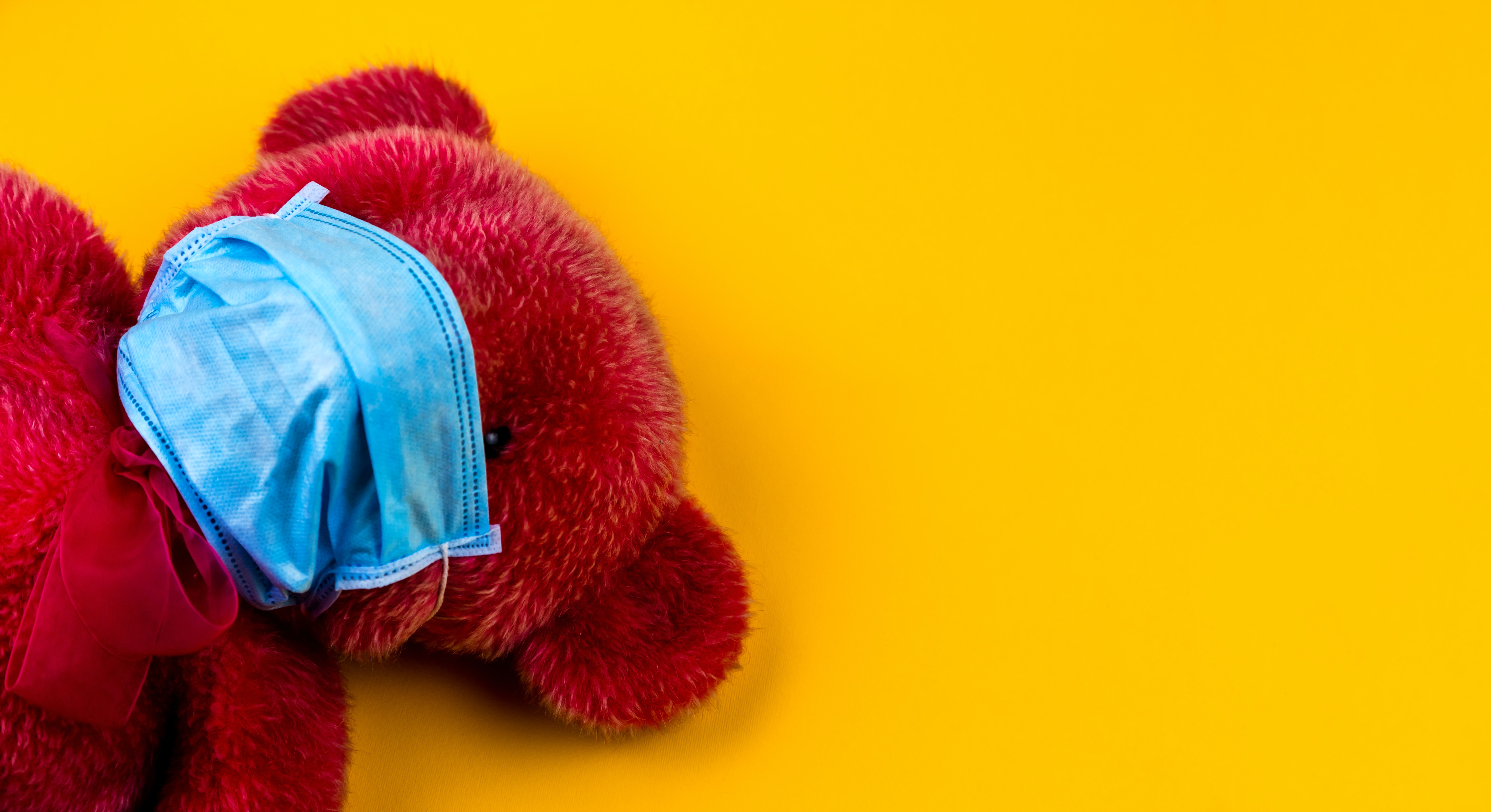 Ein roter Teddybär trägt einen Mundschutz